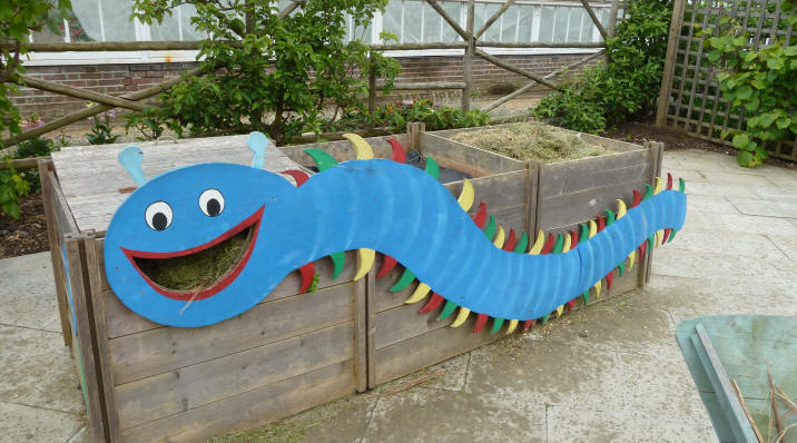 Smiling centipede sculpture on compost bins