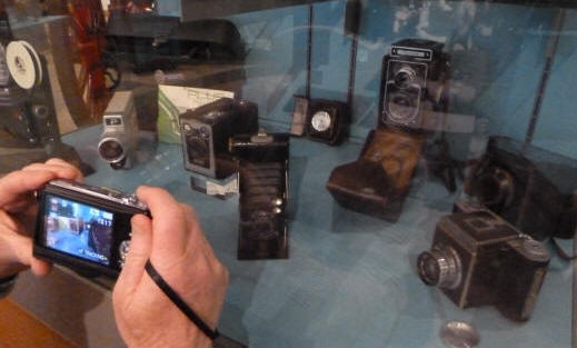 Modern digital camera taking a picture of very old cameras in museum
