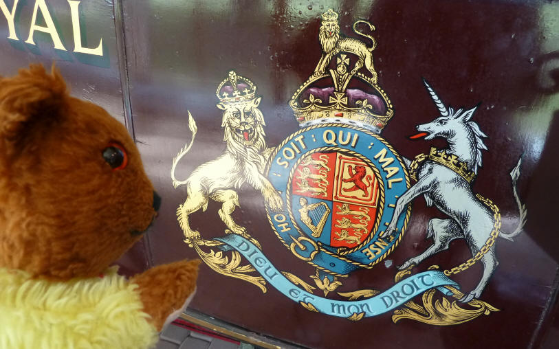 Yellow Teddy with painted coat of arms on old royal Mail carriage
