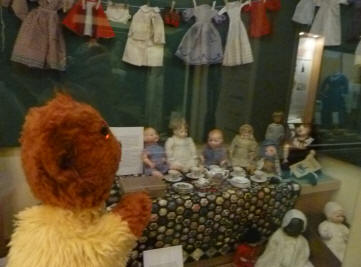 Yellow Teddy with display of dolls and clothes